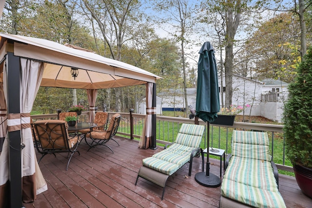 wooden deck with a gazebo, a lawn, and outdoor dining space