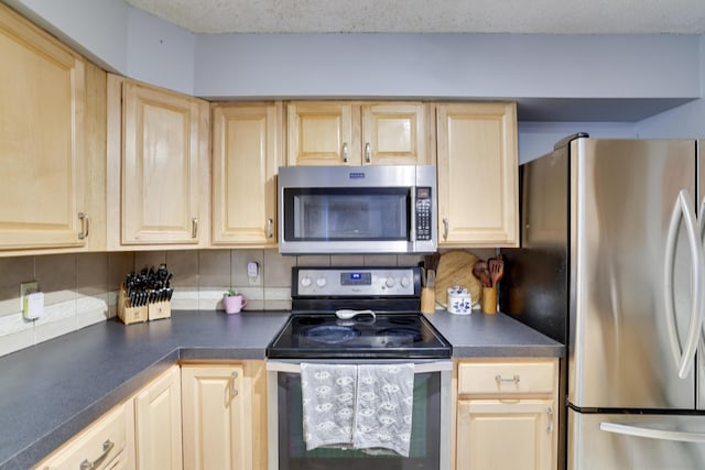 kitchen with light brown cabinetry, appliances with stainless steel finishes, and dark countertops