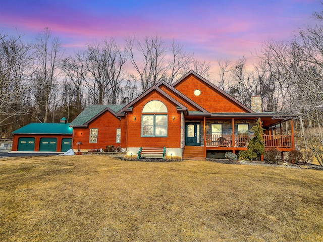 chalet / cabin with an outbuilding, covered porch, driveway, a front lawn, and a chimney