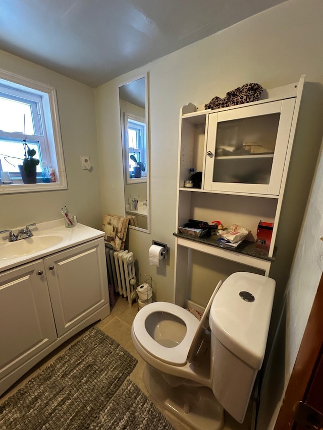 half bathroom with radiator heating unit, toilet, tile patterned flooring, and vanity
