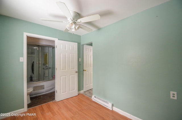 unfurnished bedroom featuring ceiling fan, baseboard heating, and light hardwood / wood-style floors