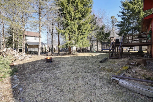 view of yard with a trampoline and an outdoor fire pit