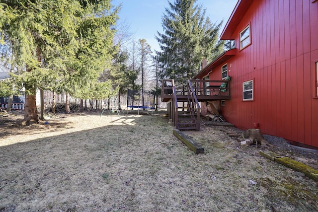 view of yard with stairs, a deck, and a trampoline