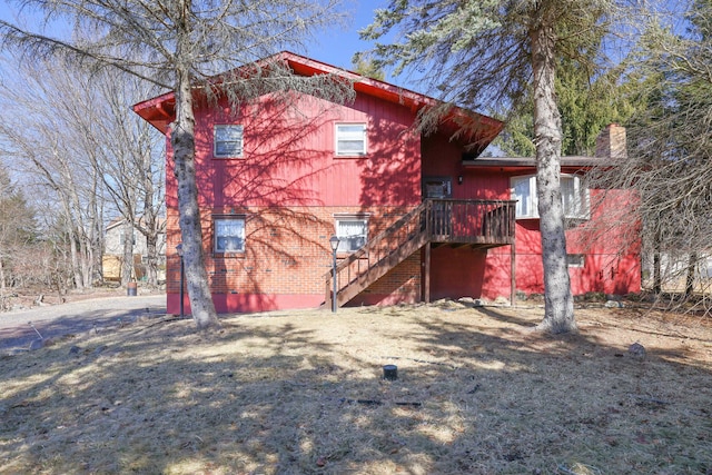 rear view of house featuring brick siding and stairway