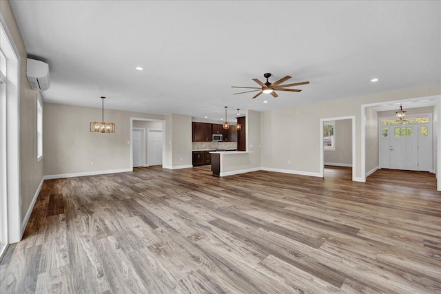 111 Parker Mews, Albrightsville, PA 18210 - unfurnished living room featuring a wall mounted air conditioner, baseboards, a ceiling fan, a chandelier, and wood finished floors