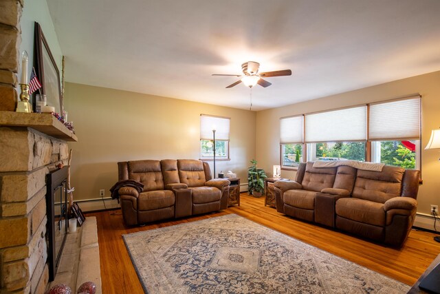 7035 Scenic Dr, Bloomsburg, PA 17815 - living room featuring ceiling fan, a stone fireplace, wood finished floors, and baseboard heating