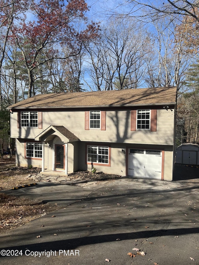 view of front facade with an attached garage, a storage unit, and an outbuilding