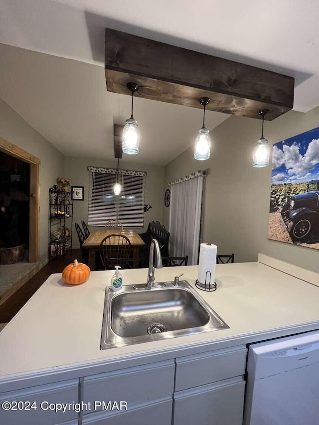 kitchen with light countertops, white dishwasher, a sink, and decorative light fixtures