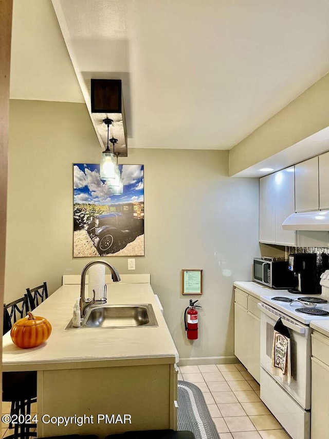 kitchen featuring light countertops, electric stove, stainless steel microwave, and a sink