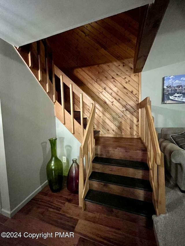 staircase with wooden ceiling, beamed ceiling, and wood finished floors