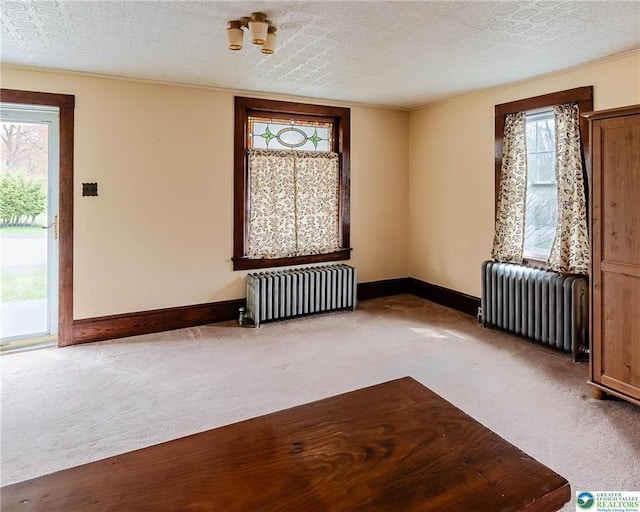 carpeted spare room with baseboards and radiator