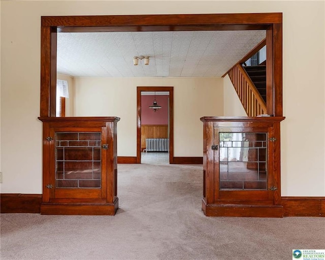corridor with carpet floors, baseboards, stairs, and radiator