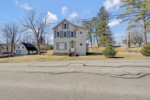 view of front of house with an outbuilding, a garage, entry steps, and a front lawn