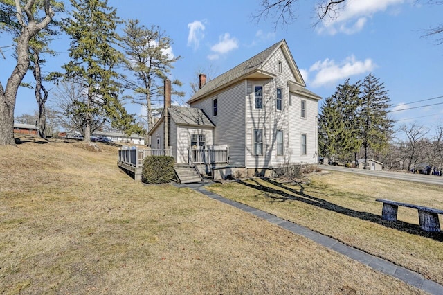 view of side of property featuring a lawn, a chimney, and a deck