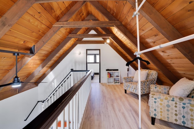 sitting room with lofted ceiling with beams, an upstairs landing, wood finished floors, and wooden ceiling