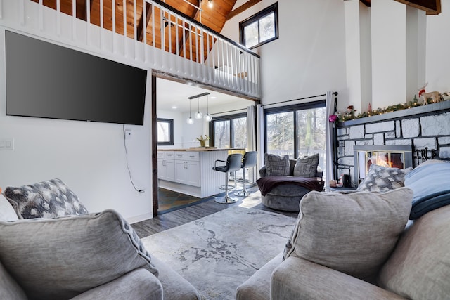 living room with high vaulted ceiling, a stone fireplace, wood ceiling, and dark wood-style flooring