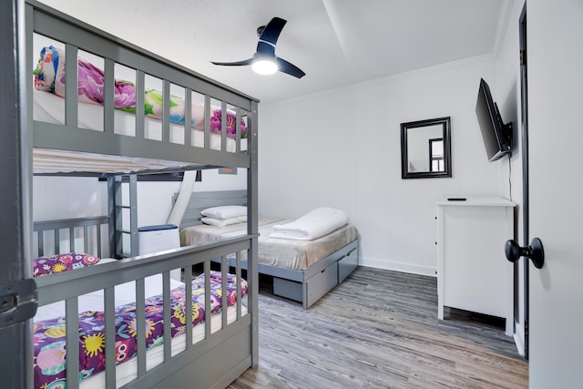 bedroom featuring ceiling fan, crown molding, baseboards, and wood finished floors