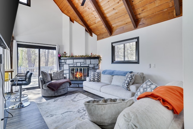 living area featuring a stone fireplace, beamed ceiling, wooden ceiling, and high vaulted ceiling