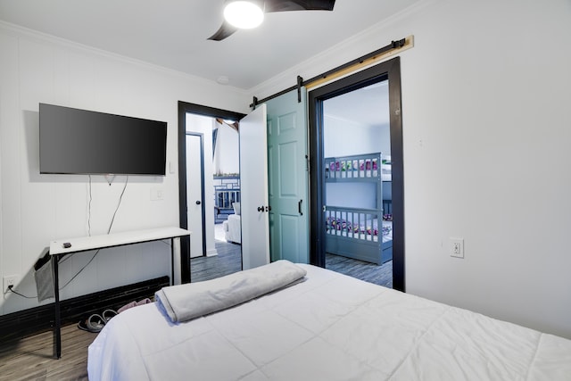 bedroom with access to exterior, a barn door, wood finished floors, and ornamental molding