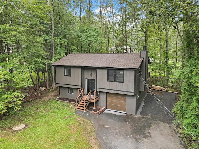 148 Acorn Ln, Kunkletown, PA 18058 - bi-level home featuring a chimney, a shingled roof, asphalt driveway, a forest view, and an attached garage