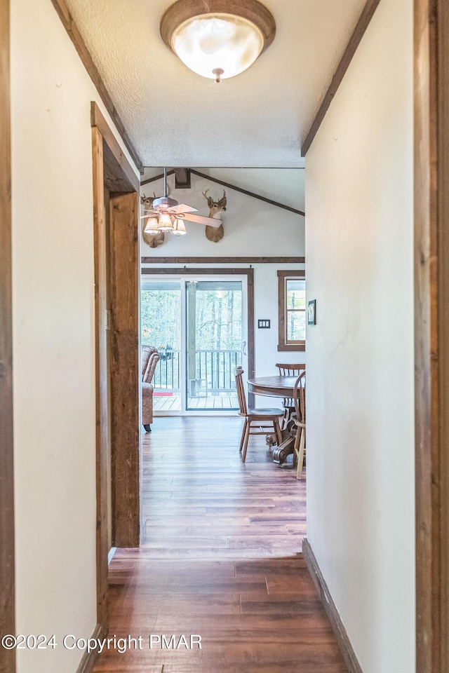 corridor featuring a healthy amount of sunlight, a textured ceiling, baseboards, and wood finished floors