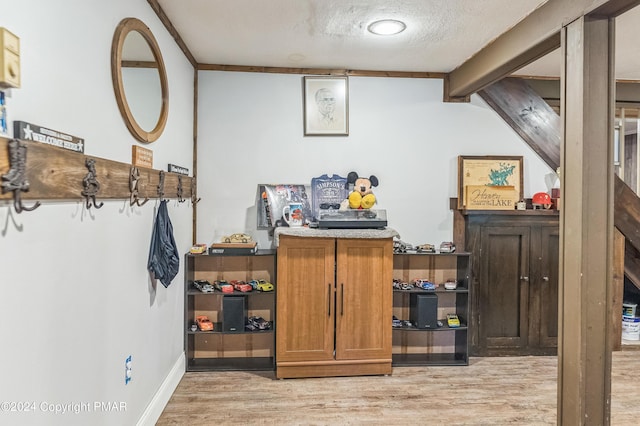 interior space with light wood-type flooring, beam ceiling, a textured ceiling, and baseboards