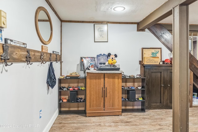 interior space with beam ceiling, baseboards, a textured ceiling, and light wood finished floors