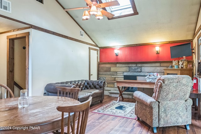 living area with a ceiling fan, a skylight, visible vents, and wood finished floors