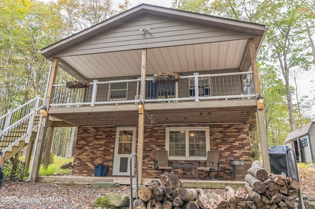 back of property with brick siding, a patio, and stairway