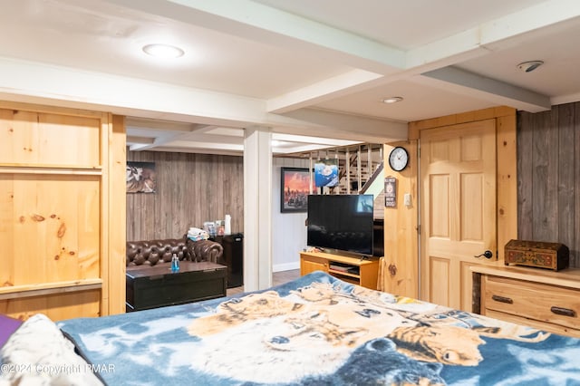 bedroom featuring wooden walls and beam ceiling