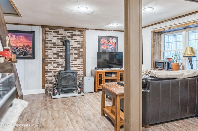 living area with baseboards, wood finished floors, a wood stove, a textured ceiling, and wood walls