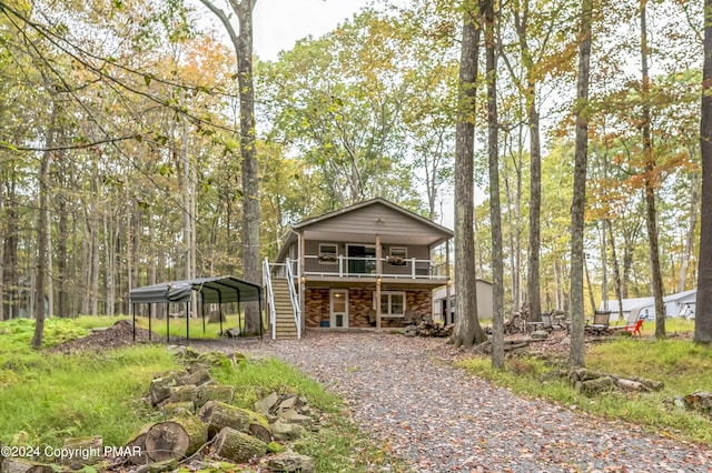 view of front facade featuring a detached carport, driveway, a deck, and stairs