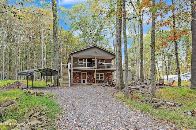 view of front of house featuring driveway, stairs, a deck, and a carport