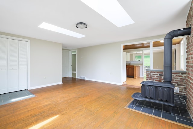 157 Hollow Rd, East Stroudsburg, PA 18302 - unfurnished living room featuring a wood stove, hardwood / wood-style floors, a skylight, and baseboards