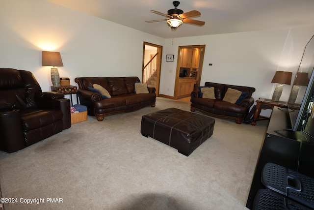 living area with a ceiling fan, carpet flooring, and stairs