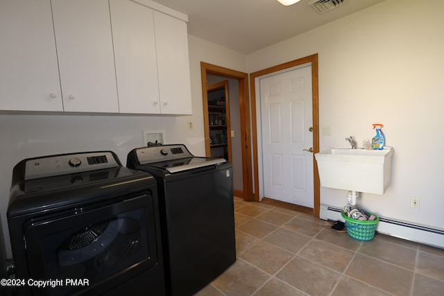 laundry room featuring washing machine and dryer, a sink, visible vents, baseboard heating, and cabinet space