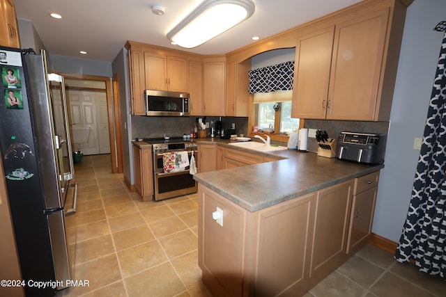 kitchen with a peninsula, light tile patterned floors, appliances with stainless steel finishes, and backsplash