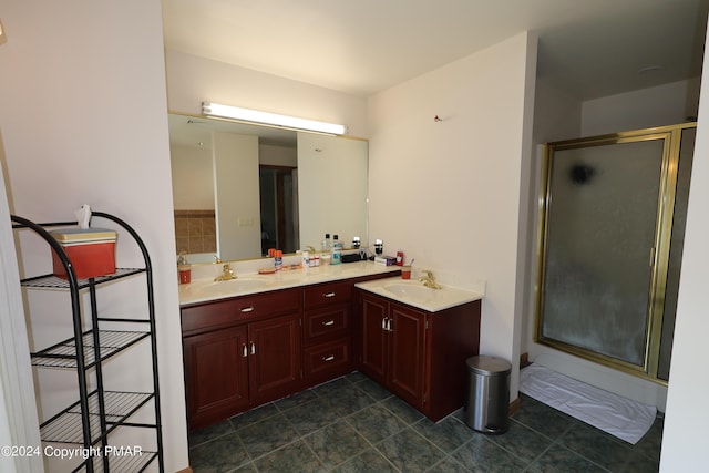 bathroom with a stall shower, a sink, and double vanity