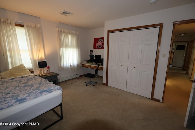 bedroom featuring a baseboard radiator, light colored carpet, visible vents, baseboards, and a closet