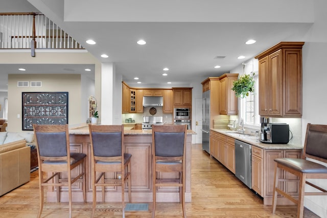 117 Morning Side Ter, East Stroudsburg, PA 18302 - kitchen featuring stainless steel appliances, light wood-style flooring, a sink, light stone counters, and under cabinet range hood