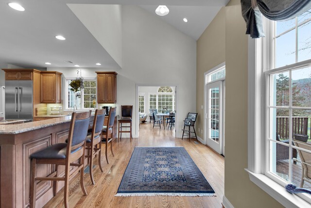 117 Morning Side Ter, East Stroudsburg, PA 18302 - kitchen with brown cabinets, a breakfast bar area, a towering ceiling, stainless steel built in refrigerator, and light stone countertops