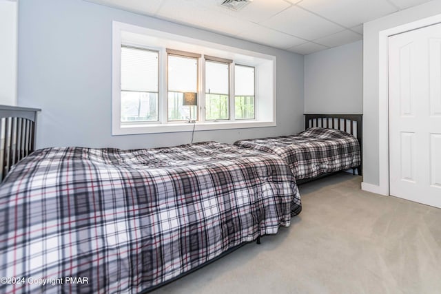 bedroom with a paneled ceiling, carpet floors, and visible vents