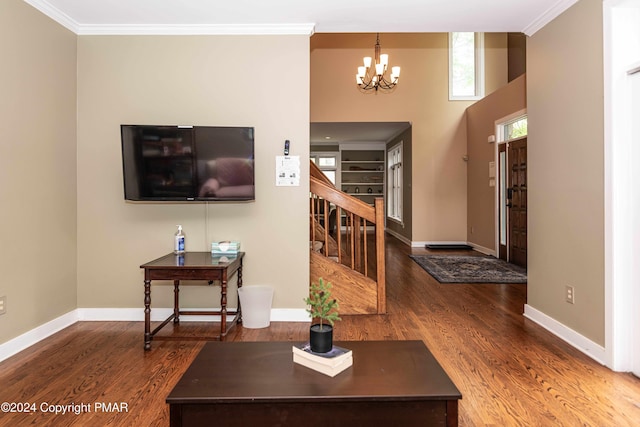 living area with a notable chandelier, wood finished floors, and ornamental molding