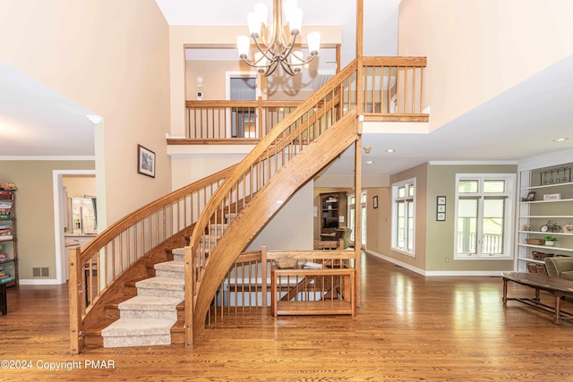 stairway with baseboards, a high ceiling, wood finished floors, and ornamental molding