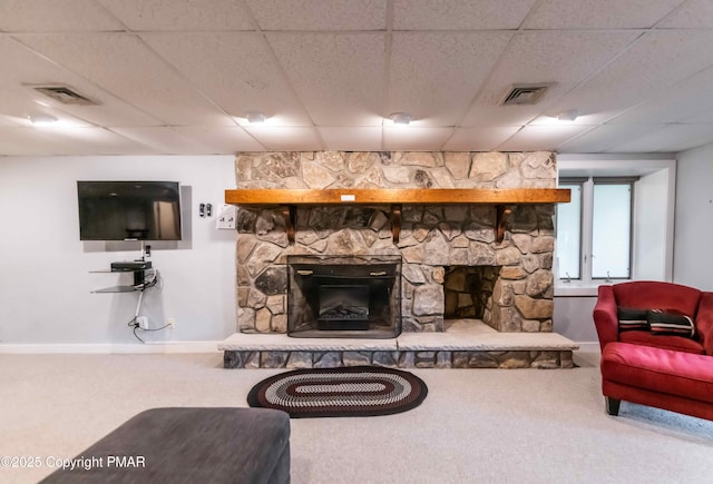 living room featuring a drop ceiling, visible vents, carpet, and a fireplace