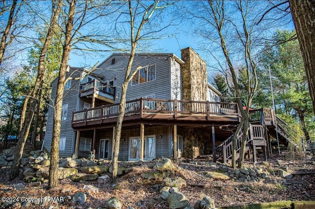 back of house with stairs, a deck, and a chimney