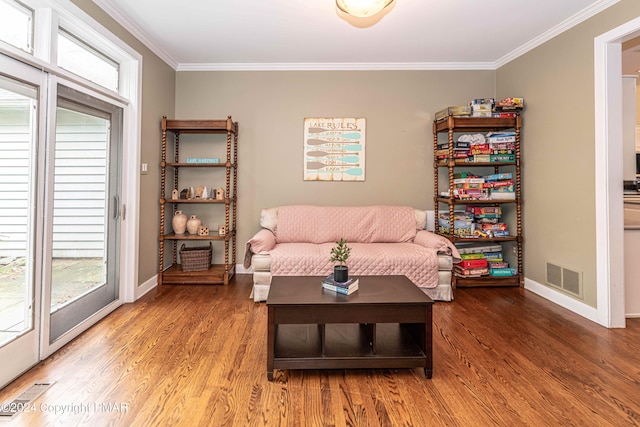 sitting room with visible vents, baseboards, wood finished floors, and ornamental molding