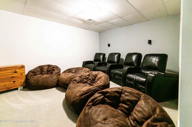 cinema room with a drop ceiling, visible vents, and carpet flooring