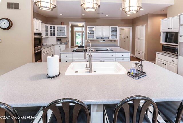 kitchen featuring visible vents, a breakfast bar, a center island with sink, recessed lighting, and appliances with stainless steel finishes