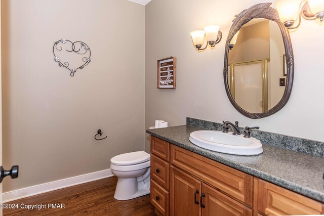 bathroom with vanity, toilet, wood finished floors, and baseboards